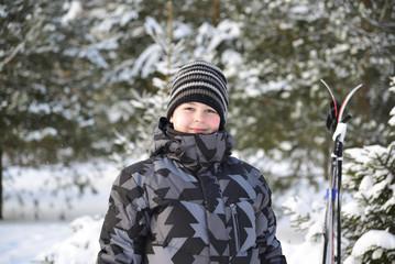 Fototapeta na wymiar Teen Boy with skis at a pine forest in winter