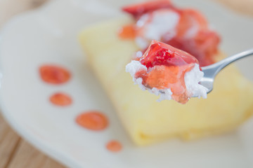 Strawberry crepe cake,White dish,Spoon,Wooden floor.