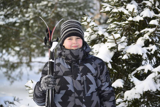 Teen Boy with skis at  a pine forest in winter