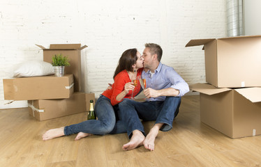 happy American couple sitting on floor unpacking together celebrating with champagne toast moving in a new house