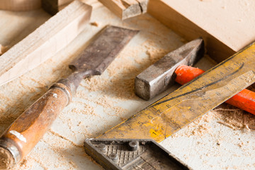 Hammer, chisel and angle carpenter lie on a workbench