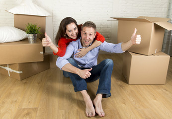 Fototapeta na wymiar young happy couple sitting on floor together celebrating moving in new flat house or apartment