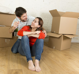 Fototapeta na wymiar happy couple sitting on floor celebrating moving in new flat house or apartment
