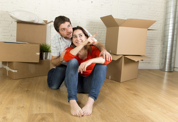 Fototapeta na wymiar happy couple sitting on floor celebrating moving in new flat house or apartment