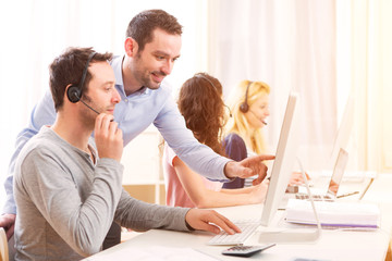 Manager training a young attractive people on computer