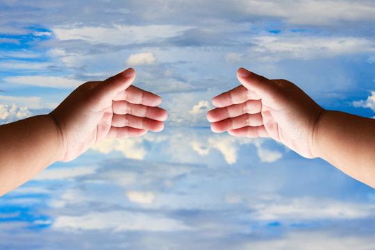 Outstretched cupped hands of young girl on blue sky.