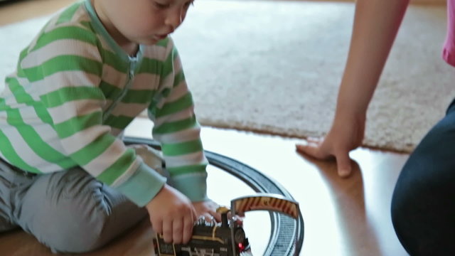 Little boy with mother playing with toy train
