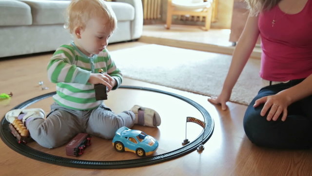 Little boy with mother playing with toy train