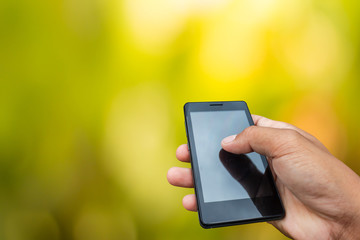 Hand hold and touch screen smart phone, tablet,cellphone on day noon light with green blurred nature background.