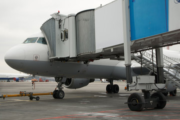 Airplane docked to mobile telescopic bridge in the airport