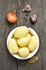 Peeled potatoes on wooden background