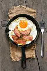 Fried eggs with bacon on wooden background