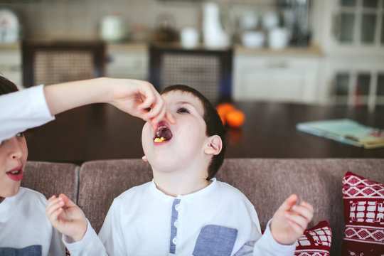 Two Boys Eating Popcorn On A Sofa In The Dining Room