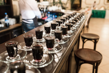 Many cups of coffee standing at the bar in the background.