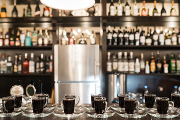 Many cups of coffee standing at the bar in the background.