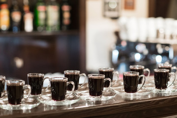 Many cups of coffee standing at the bar in the background.