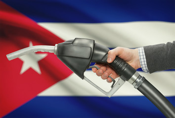 Fuel pump nozzle in hand with national flag on background - Cuba