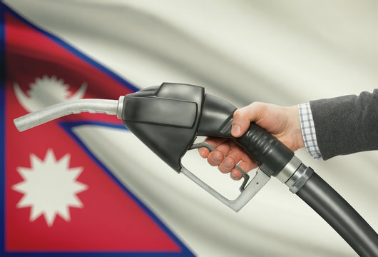 Fuel Pump Nozzle In Hand With National Flag On Background - Nepal