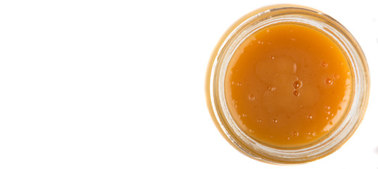 Orange fruit curd in glass jar over white background