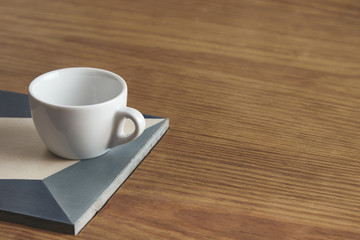 Blank white coffee cup on ceramic plate on thick wooden table in