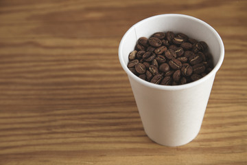 Blank white paper cup with good roasted coffee beans