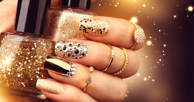 Golden manicure with gems and sparkles. Bottle of nailpolish, trendy accessories