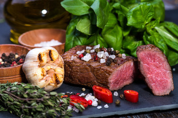  Beef Steak, medium, salt, pepper, garlic, rosemary  on the black board, background.