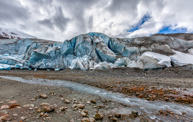 Glacier in Alaska, close up with blue ice and a stream of melted water in the foreground. Shows climate change impact