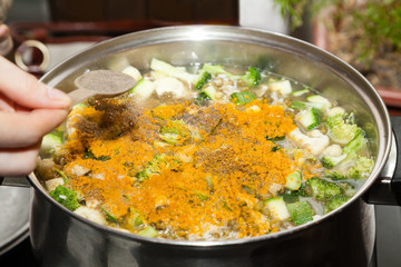Adding spices to vegetable soup 
