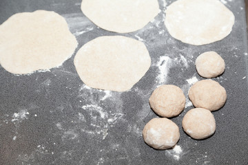 Fototapeta na wymiar Bunch of flour dough and buns on table