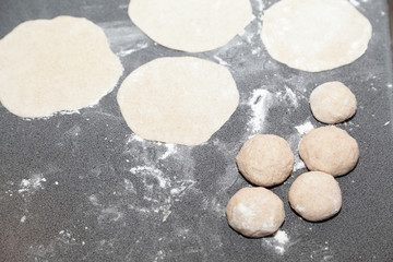 Bunch of flour dough and buns on table