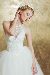 Fototapeta premium Woman in Weddind dress posing on gold background