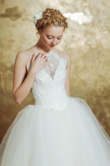 Woman in Weddind dress posing on gold background