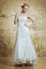 Woman in Weddind dress posing on gold background