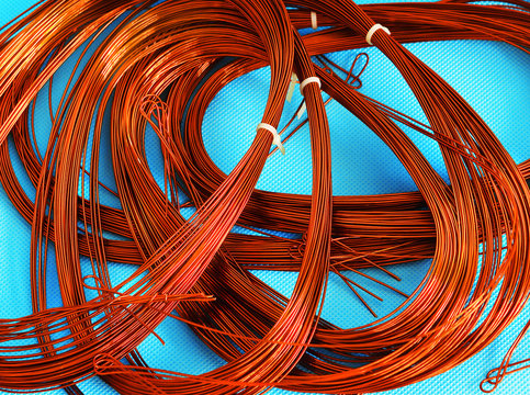 Skein of coated copper wire. Orange copper wire on light blue background