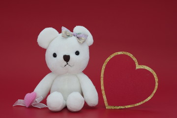 A white doll and golden heart with red background
