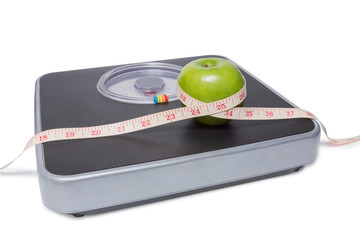close up of scale, tape and apple isolated on white