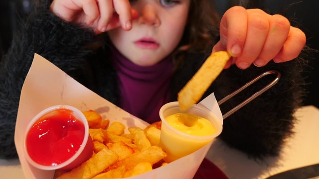 jolie enfant mangeant des frites