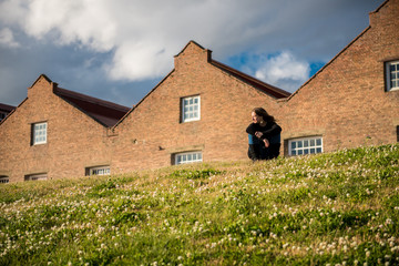 Woman sitting on the grass in front of an old building