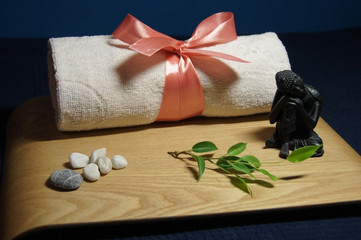 Fototapeta na wymiar Ароматерапия с зеленой веточкой, полотенцем, морскими камнями и статуей Будды