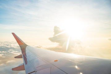 Wing of airplane on cloud sky from window in morning.