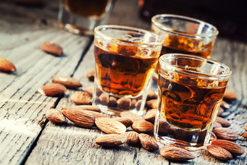 Italian amaretto liqueur with dry almonds on the old wooden back
