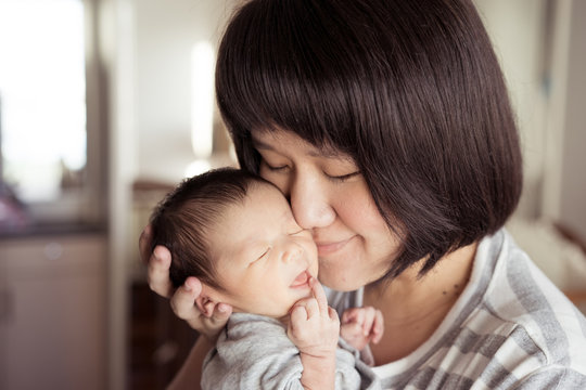 Asian mother holds her  newborn baby