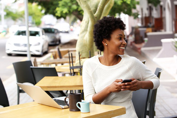 Happy young woman sitting at cafe with a mobile phone