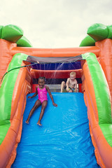 Happy smiling children playing on an inflatable slide bounce house