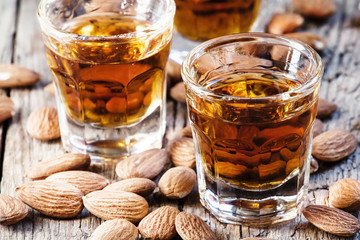Italian amaretto liqueur with dry almonds on the old wooden back