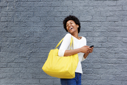 Smiling Young African Woman With Mobile Phone Looking Away