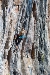 Young Rock Climber ascending steep colorful rocky Wall Lead Climbing