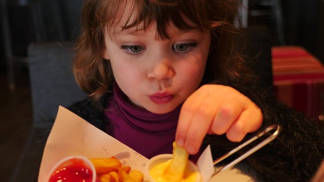 jolie enfant mangeant des frites