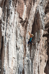 Blond Female Climber ascending Vertical Orange Rock